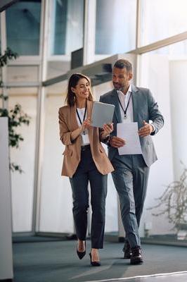 Smiling businesswoman and her coworker using digital tablet while walking through the office.